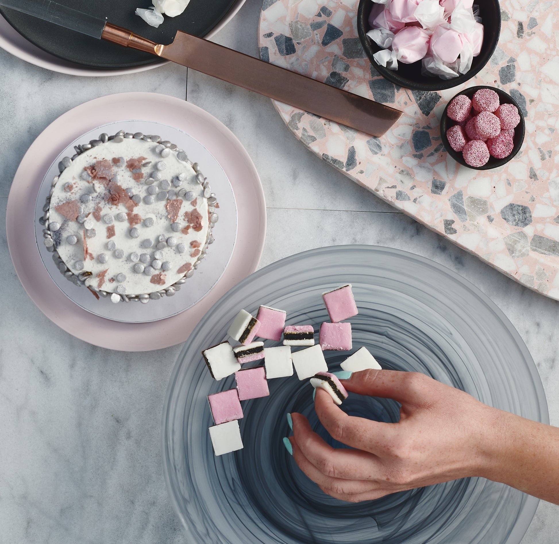 Hand grabbing for candy next to a cake