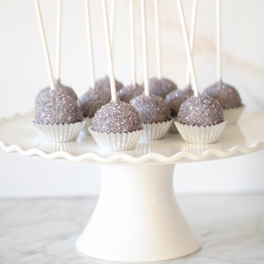 silver sprinkle cake pops on a white cake stand